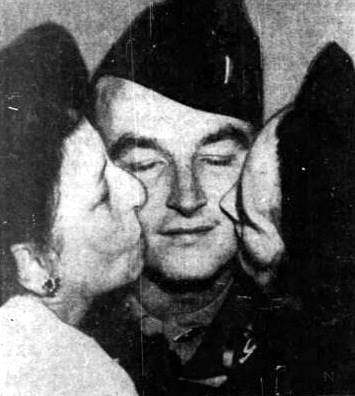 Lt. Richard A Bauer, center, gets a
welcome home kiss from his mother and wife.