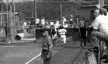 Manager Joe Powers watches a drive
to the outfield on opening day, 1976, as
Chris Brendel crosses the plate for a run.